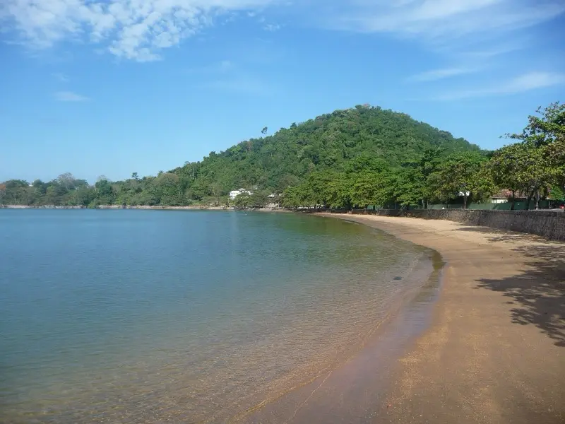 Calm sea and a quiet sandy beach at Kep, with a forested hill behind